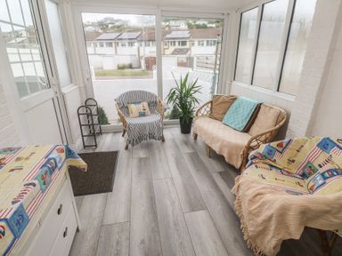 A conservatory with chairs and a table at 16 Forth An Nance in Portreath
