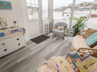 A conservatory with a sofa and chair at 16 Forth An Nance in Portreath