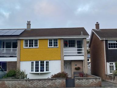 A house with yellow exterior and solar panels at 16 Forth An Nance in Portreath