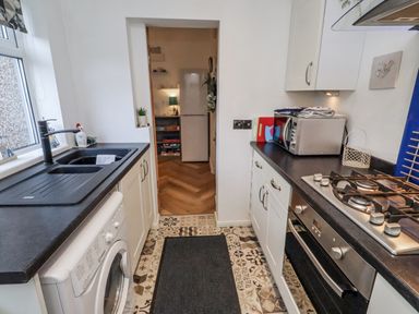 A kitchen with a sink and gas stove at 55 Meldon terrace in Newbiggin-by-the-Sea