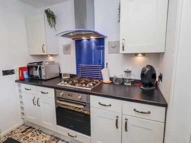 A kitchen with a gas stove and microwave at 55 Meldon terrace Newbiggin-by-the-Sea