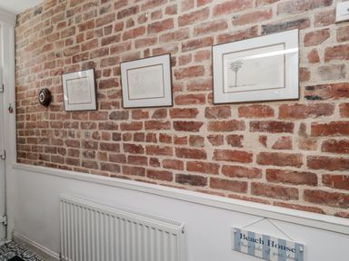 A hallway with framed artwork on brick wall at 55 Meldon terrace Newbiggin-by-the-Sea