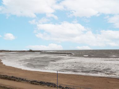 A beach with waves and a pier at 55 Meldon terrace in Newbiggin-by-the-Sea