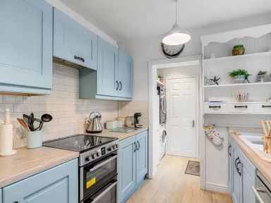 A kitchen with blue cabinets and appliances at Bay Tree Cottage in Heacham