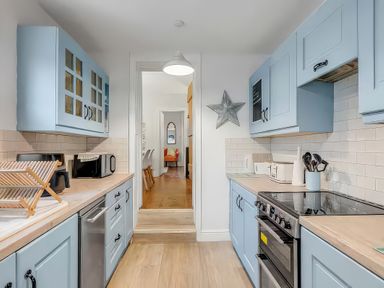 A kitchen with blue cabinets and a stove at Bay Tree Cottage in Heacham