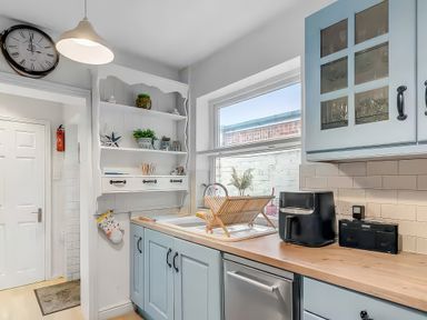 A kitchen with a sink and shelf at Bay Tree Cottage in Heacham