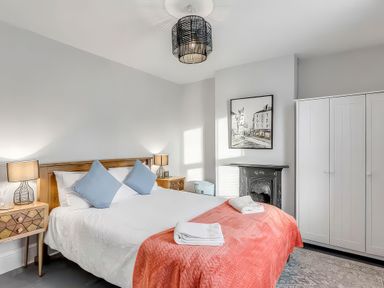 A bedroom with a bed, nightstands, and a wardrobe at Bay Tree Cottage Heacham