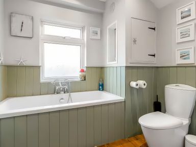 A bathroom with a bathtub and toilet at Bay Tree Cottage in Heacham