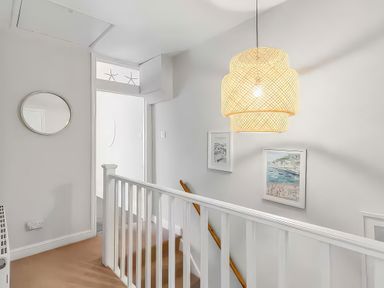 A hallway with a light fixture and wall art at Bay Tree Cottage in Heacham