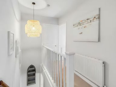 A hallway with a light fixture and a painting at Bay Tree Cottage Heacham