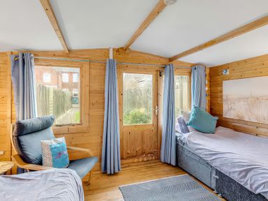 A bedroom with two beds and an armchair at Bay Tree Cottage in Heacham