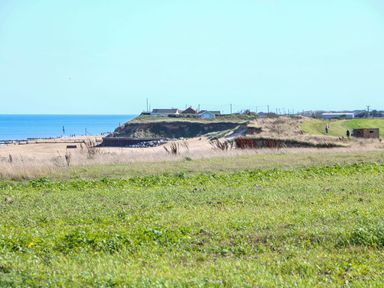 A view of the ocean and shore with grassy hills at The Ivy in Norwich