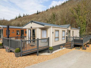 A caravan with decks and flower pots at 33 Woodpecker Lodge Llanarth
