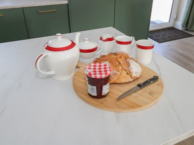 A kitchen with a teapot, teacups, bread, and jam on a wooden board at Doire Fhatharta Beag, Carraroe, County Galway