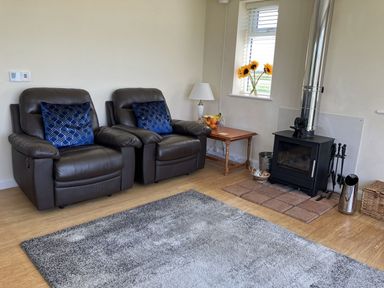 A living room with recliner chairs and a wood burning stove at Seadrift near Happisburgh