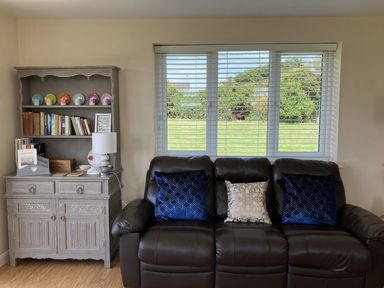 A living room with a sofa and bookshelf at Seadrift Bush Estate near Happisburgh
