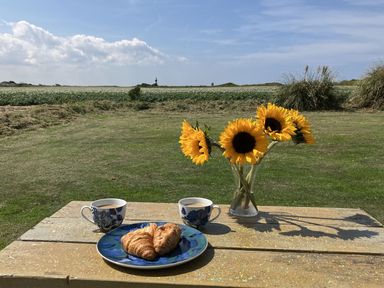 A table with coffee, croissant, and sunflowers at Seadrift in Bush Estate near Happisburgh