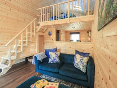 A living room with a sofa and stairs at Bluebelle - Crossgate Luxury Glamping in Hartsop