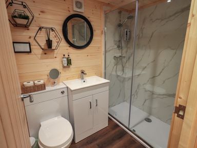 A bathroom with a shower, sink, and toilet at Bluebelle - Crossgate Luxury Glamping in Hartsop