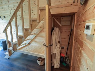 A staircase and storage area with a robe and basket at Bluebelle - Crossgate Luxury Glamping Hartsop