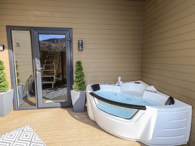 An outdoor area with a hot tub and a door at Bluebelle - Crossgate Luxury Glamping in Hartsop
