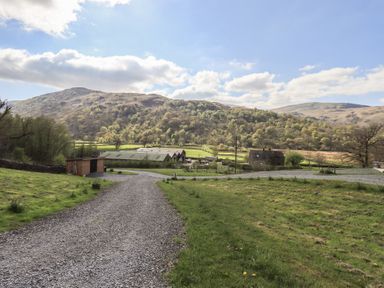 A gravel road leading through fields with mountains in the background at Bluebelle - Crossgate Luxury Glamping Hartsop