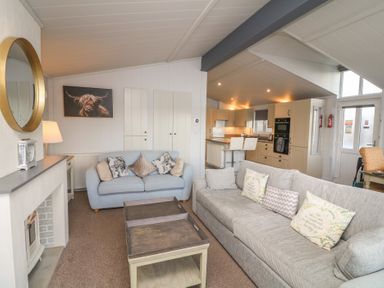 A living room with sofas and a kitchen area at Fairways 22 in Lincoln