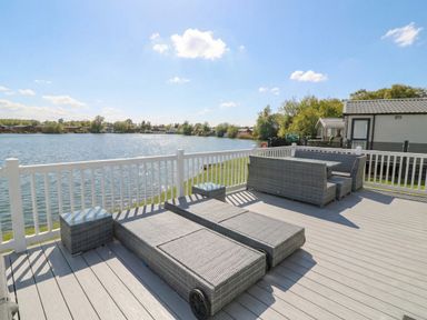 A deck overlooking water with seating at Fairways 22 in Tattershall