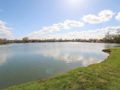 A lake with grass and trees at Fairways 22 Tattershall
