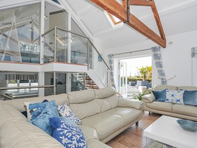 A living room with sofas and a staircase at The Cowshed in Portscatho