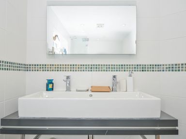 A sink and mirror with toiletries in the bathroom at The Cowshed in Portscatho