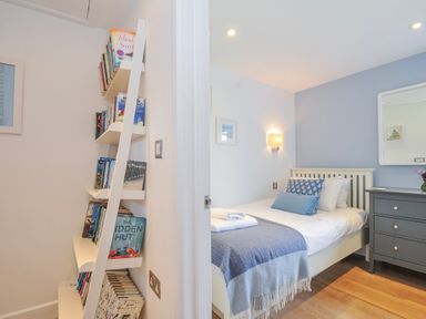 A bedroom with a bed and bookshelf at The Cowshed in Portscatho
