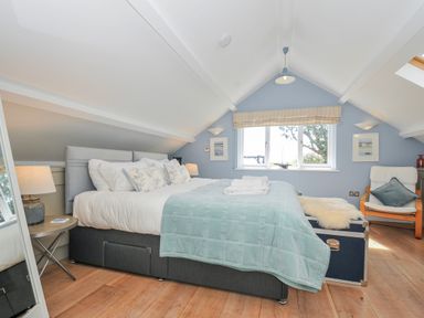 A bedroom with a bed and a chair at The Cowshed in Portscatho