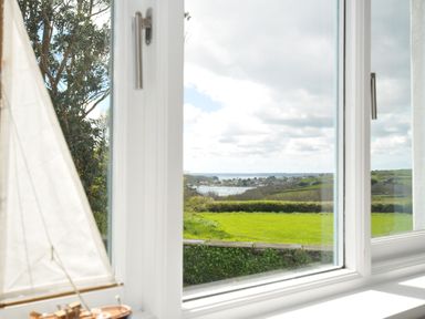 A view from a window showing a sailboat model and landscape at The Cowshed in Portscatho