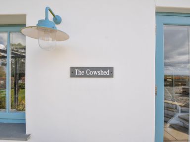 An exterior view with a sign reading The Cowshed at The Cowshed in Portscatho