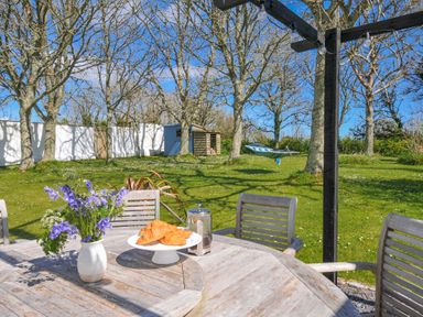A garden with a table of croissants and flowers at The Cowshed in Portscatho