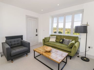 A living room with a sofa, armchair, table, and lamp at Ty Mawr Farm in Llanfairpwllgwyngyll