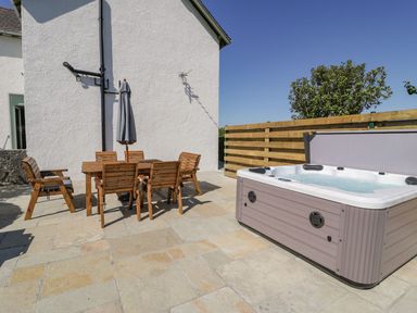 An outdoor area with a hot tub and patio furniture at Ty Mawr Farm in Llanfairpwllgwyngyll