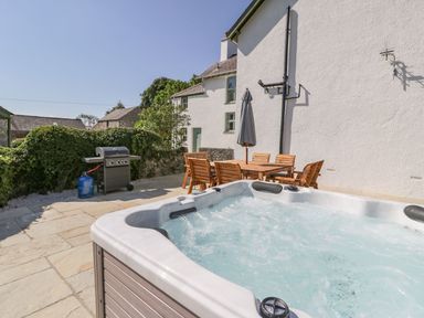 A garden with a hot tub and a dining area at Ty Mawr Farm Llanfairpwllgwyngyll