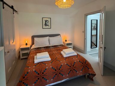 A bedroom with a bed, bedside tables, towels, and an artwork at Ty Mawr Farm Penmynydd near Llanfairpwllgwyngyll