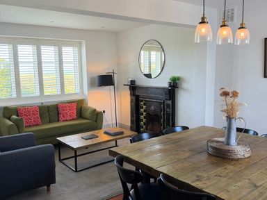 A living room with a green sofa and wooden dining table at Ty Mawr Farm Penmynydd near Llanfairpwllgwyngyll