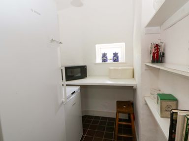 A kitchen with a refrigerator, countertop, and microwave at Cynefin in Newport, Pembrokeshire