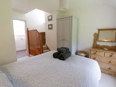 A bedroom with towels on the bed and a dressing table at Cynefin in Newport, Pembrokeshire