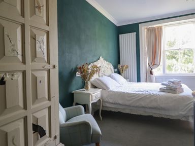 A bedroom with a bed and armchair at Plas Dolguog in Machynlleth