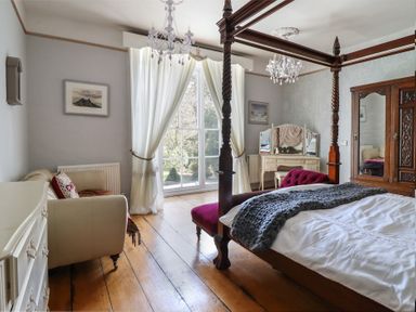 A bedroom with a four-poster bed and a dresser at Plas Dolguog in Machynlleth