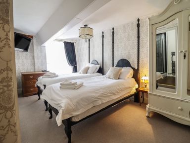 A bedroom with two beds and a wardrobe at Plas Dolguog in Machynlleth