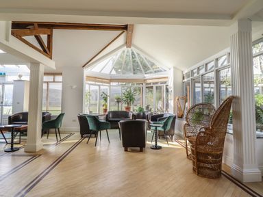 A conservatory with seating and plants at Plas Dolguog in Machynlleth