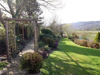 A garden with a pathway and trellis at Plas Dolguog in Machynlleth