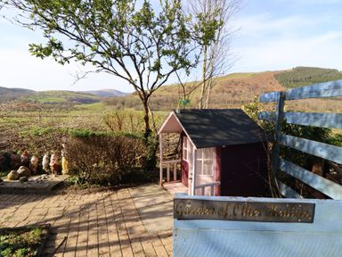 A garden with a playhouse and gnomes at Plas Dolguog in Machynlleth