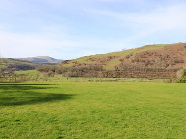 A landscape with hills and grass at Plas Dolguog in Machynlleth